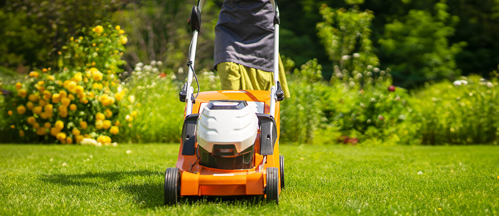 Homeowner cutting his lawn on a suburban lot with a gasoline lawn mower.